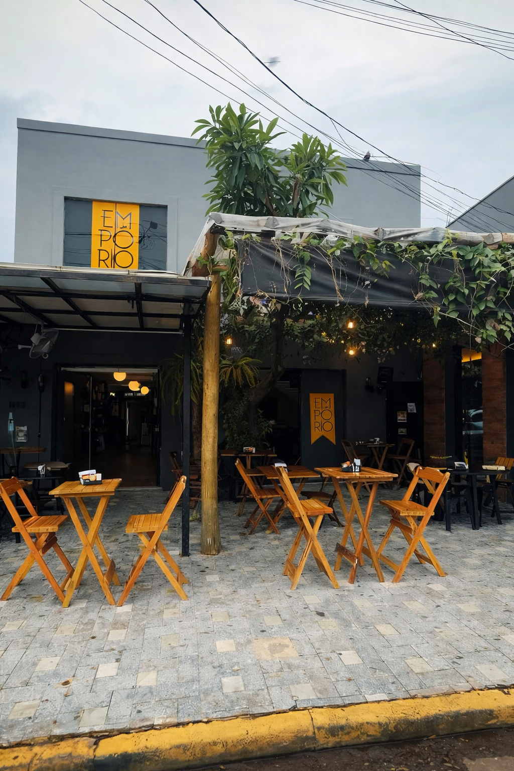 Fachada diurna do Empório Gourmet com mesas externas